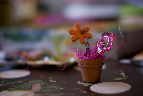 En blomma behövs till skokartongshuset. Material: Ståltråd, tyg och plastblomma, fluff & en keramikkruka.