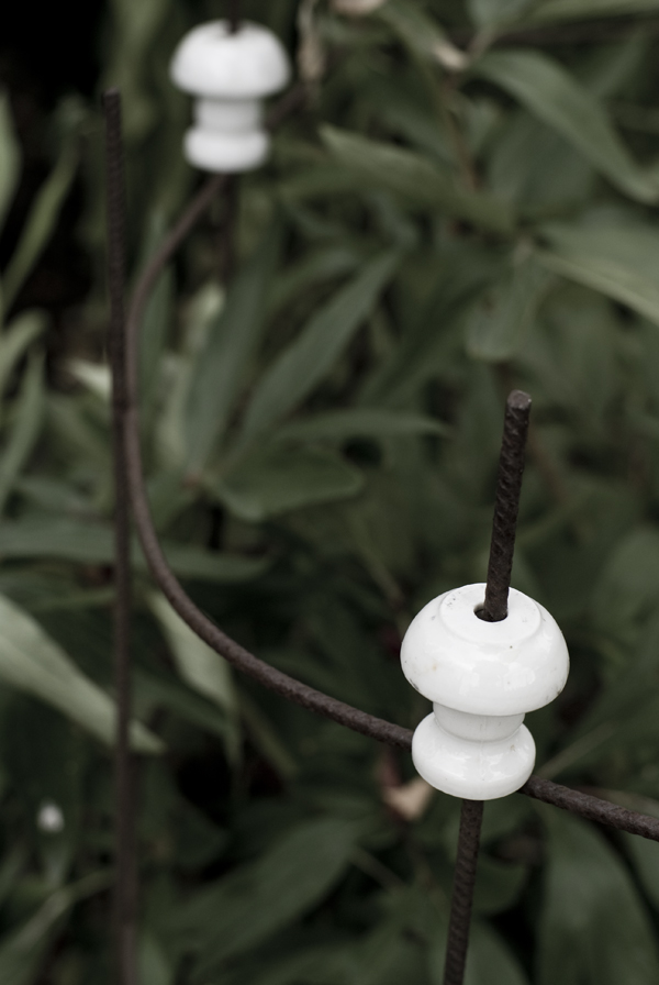 Armeringsjärn och gamla el-porslins-delar har blivit ett blomstöd i rabatten...
